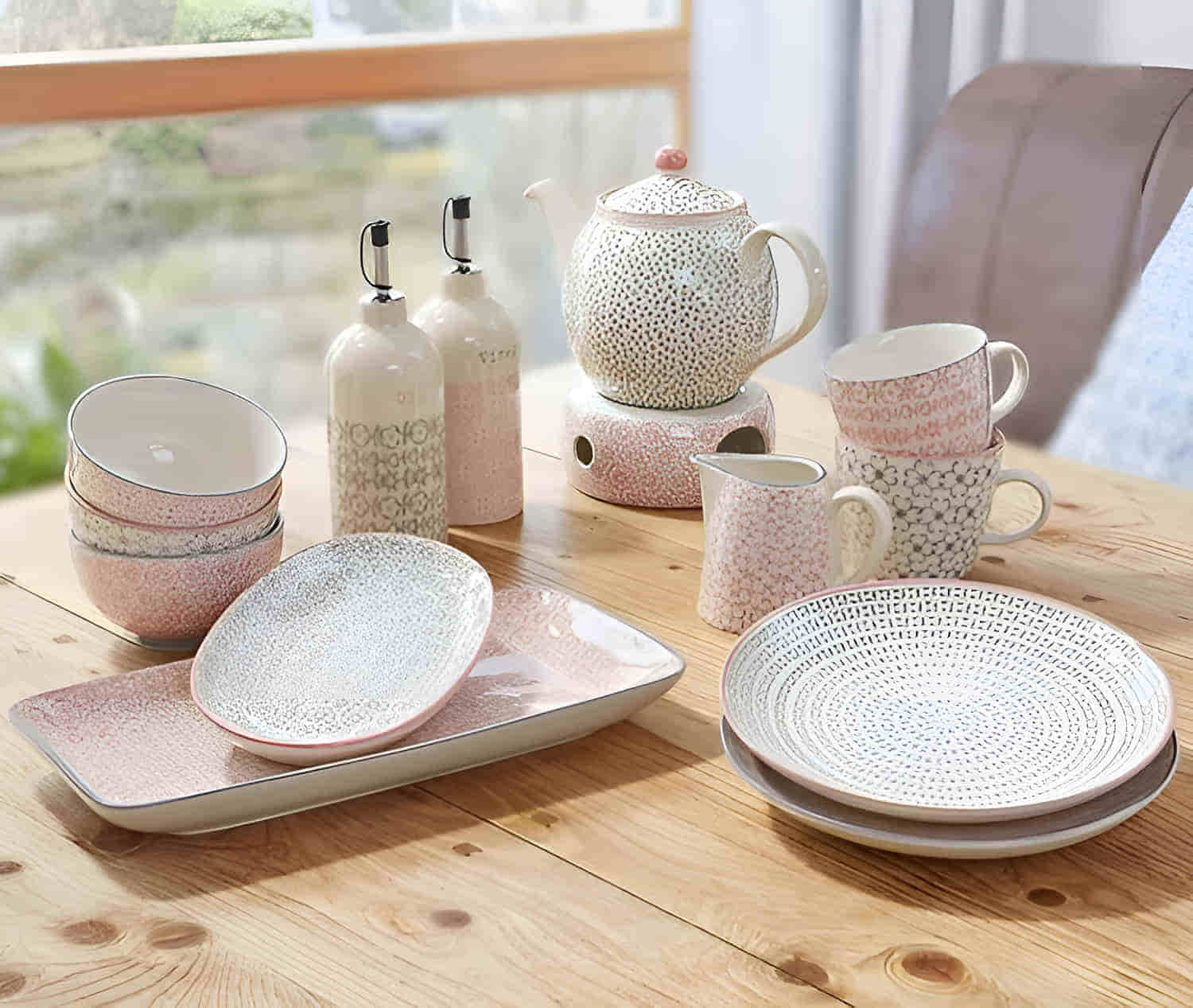 Ein großes Bloomingville Cecile Set mit 2 Teller, 2 Servierteller, 3 Schalen, 2 Becher, Kännchen und Kanne mit Stövchen auf einem braunen Tisch