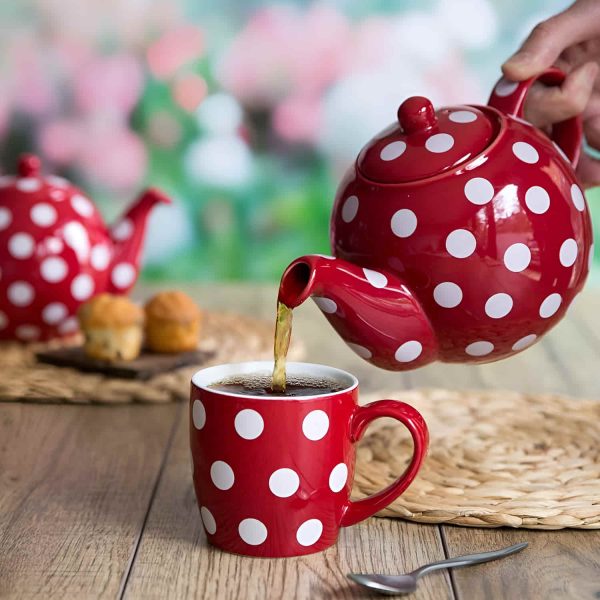Motivbild Teekanne London Pottery dots rot mit weißen Punkten beim Kaffee einschenken in einen Becher mit Henkel auf braunem Tisch